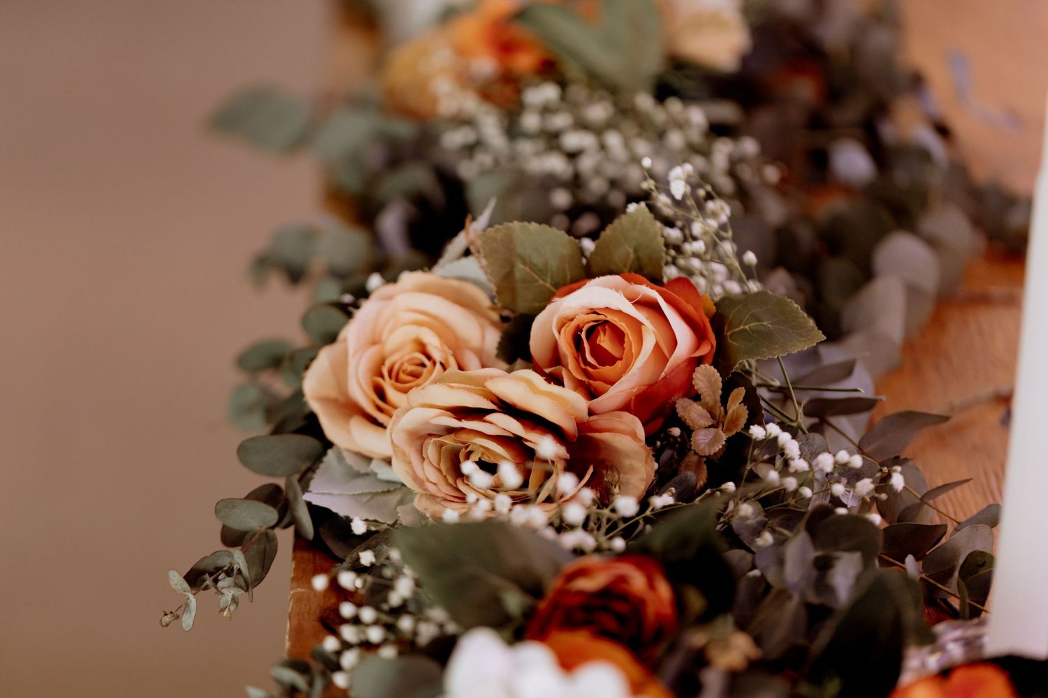 Romantic floral arrangement of peach roses and baby's breath decorates a wedding setting.