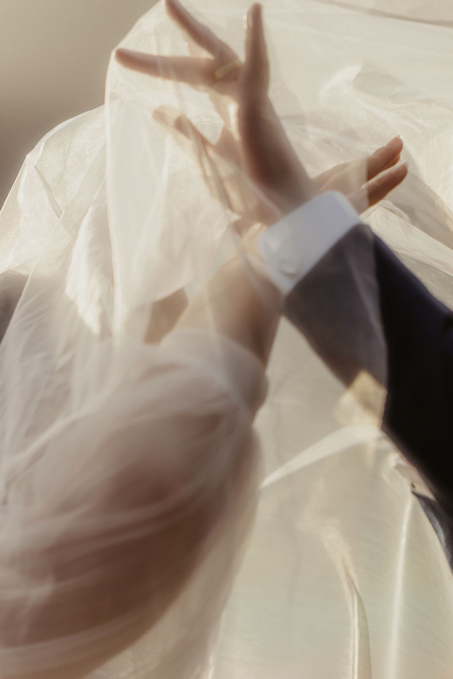 A hand presses against a translucent white plastic sheet creating shadows and texture in a minimalist composition.