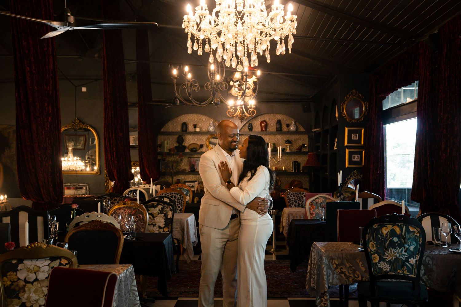 A dimly lit ballroom with elegant crystal chandeliers and couples dancing during a romantic evening celebration.