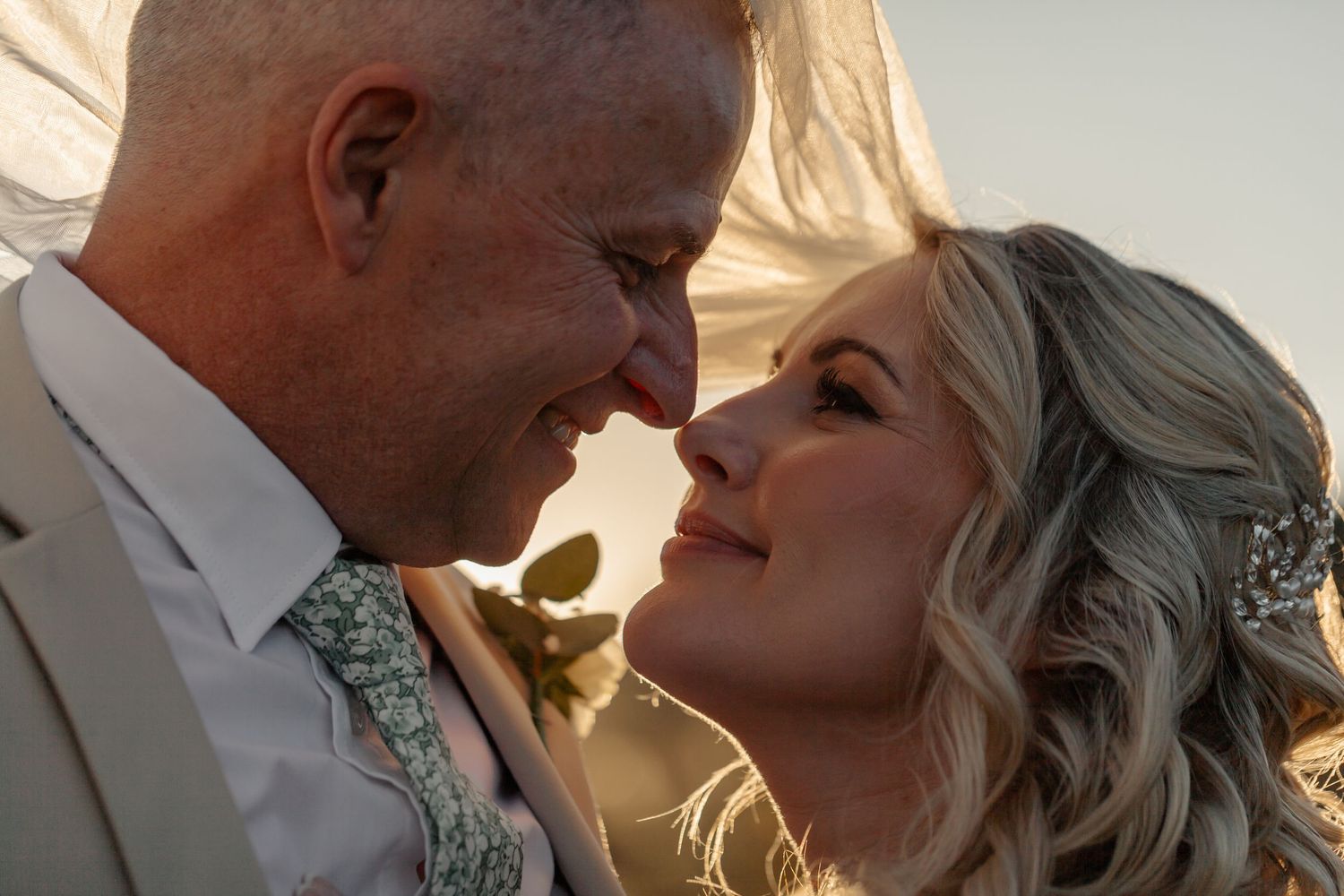 A happy couple shares an intimate moment at sunset during their wedding celebration.
