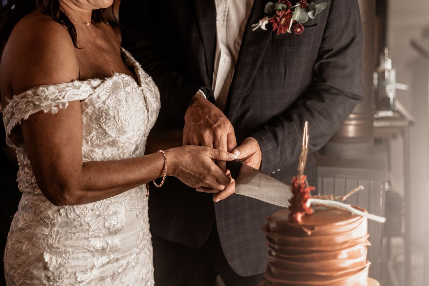 Couple cutting into a copper-colored wedding cake during reception ceremony while exchanging rings.