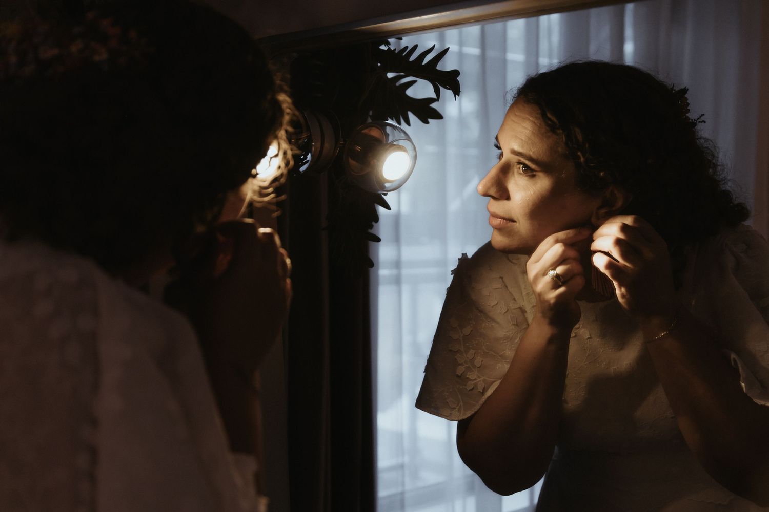 A silhouetted figure stands in dramatic lighting against a window, creating a moody atmospheric portrait.