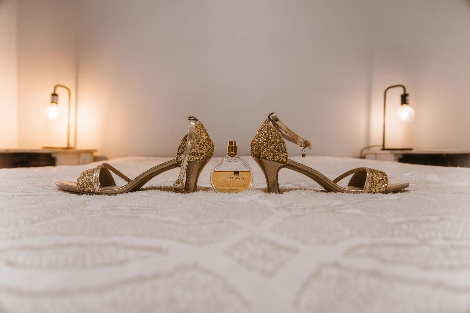 Glittery gold high heel sandals displayed on white bedding in a series of artistic product photos.