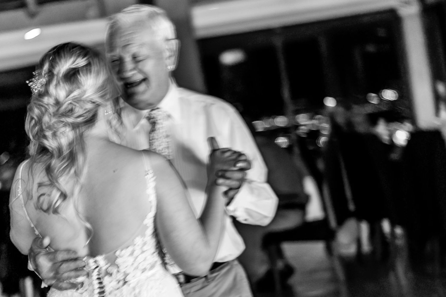 A black and white candid photo shows a tender moment during a wedding dance on the dance floor.