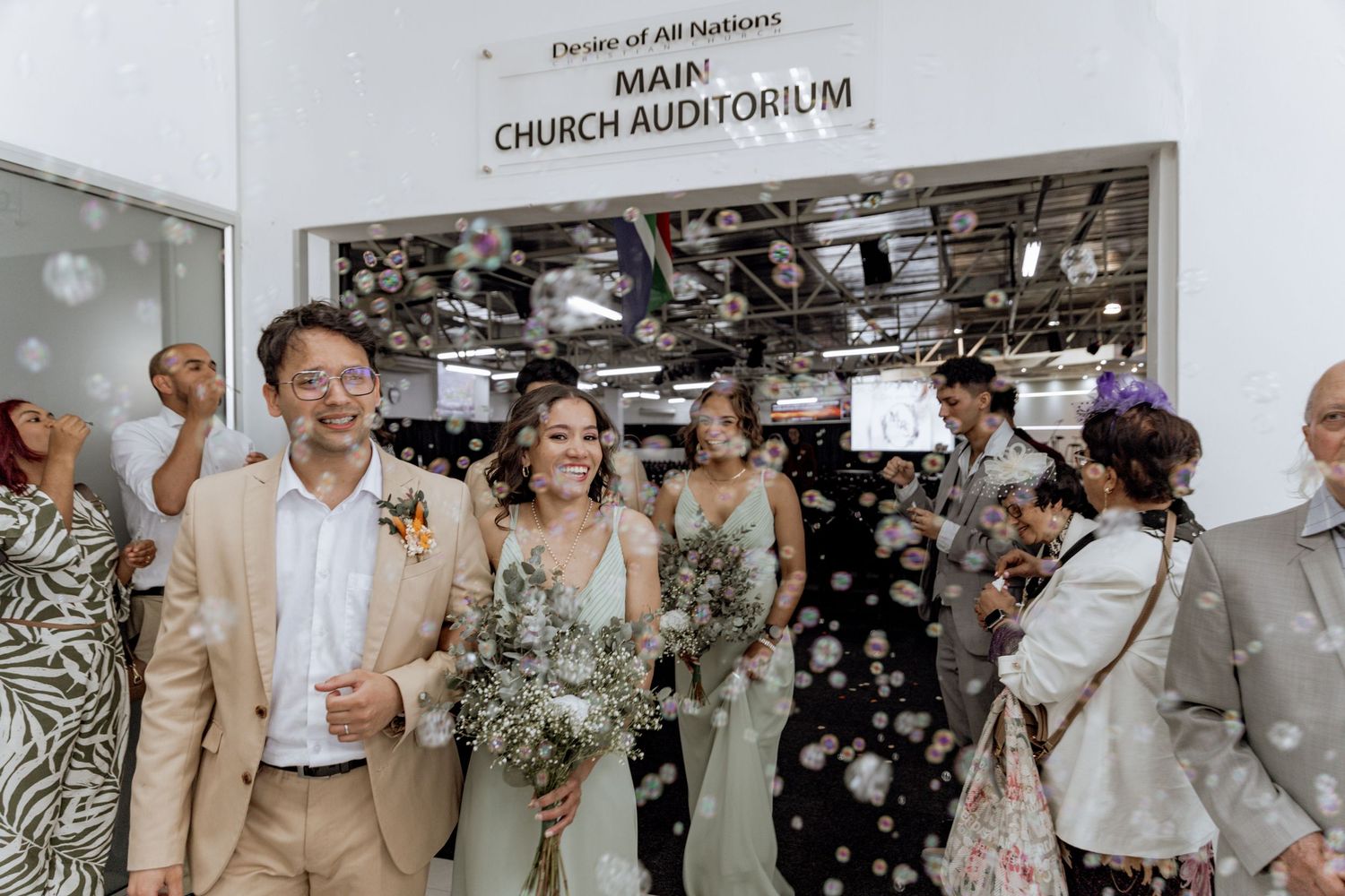 Wedding party enjoys joyful photo session moments with bubbles in outdoor celebration and candid happiness.