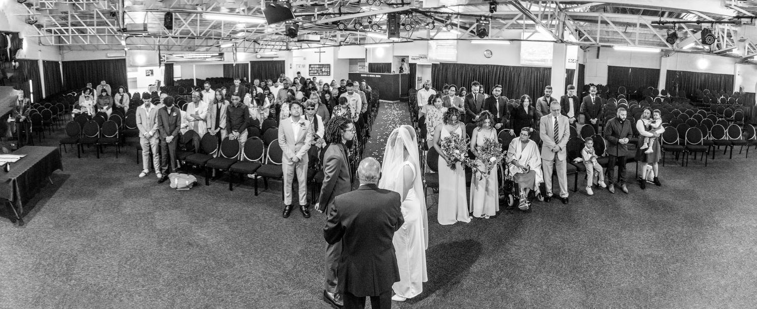 A black and white panoramic view shows a large crowd gathering for a historic event in an outdoor urban setting.