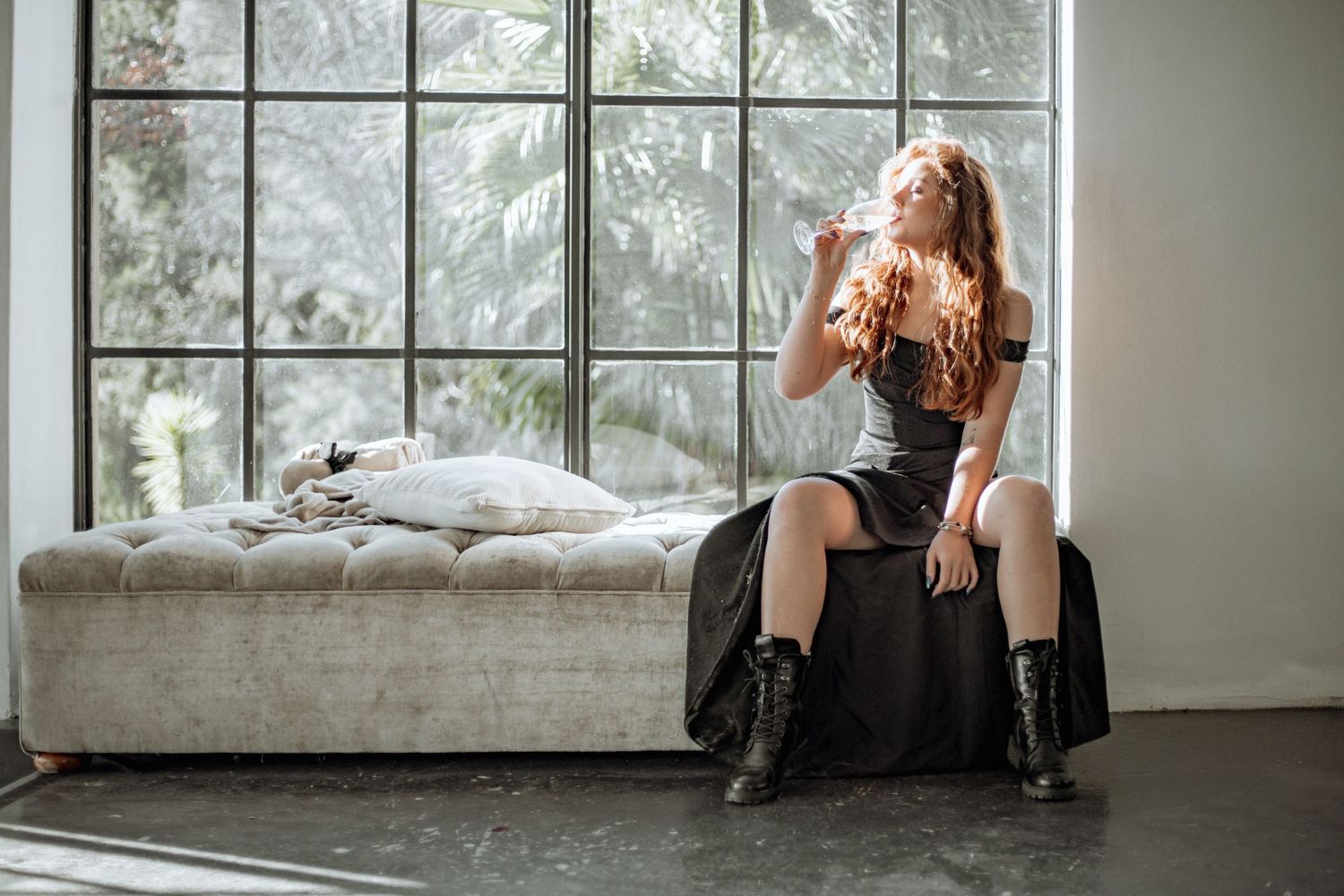 Fashion model poses during a conceptual indoor photo shoot in an industrial studio space with natural lighting and windows.
