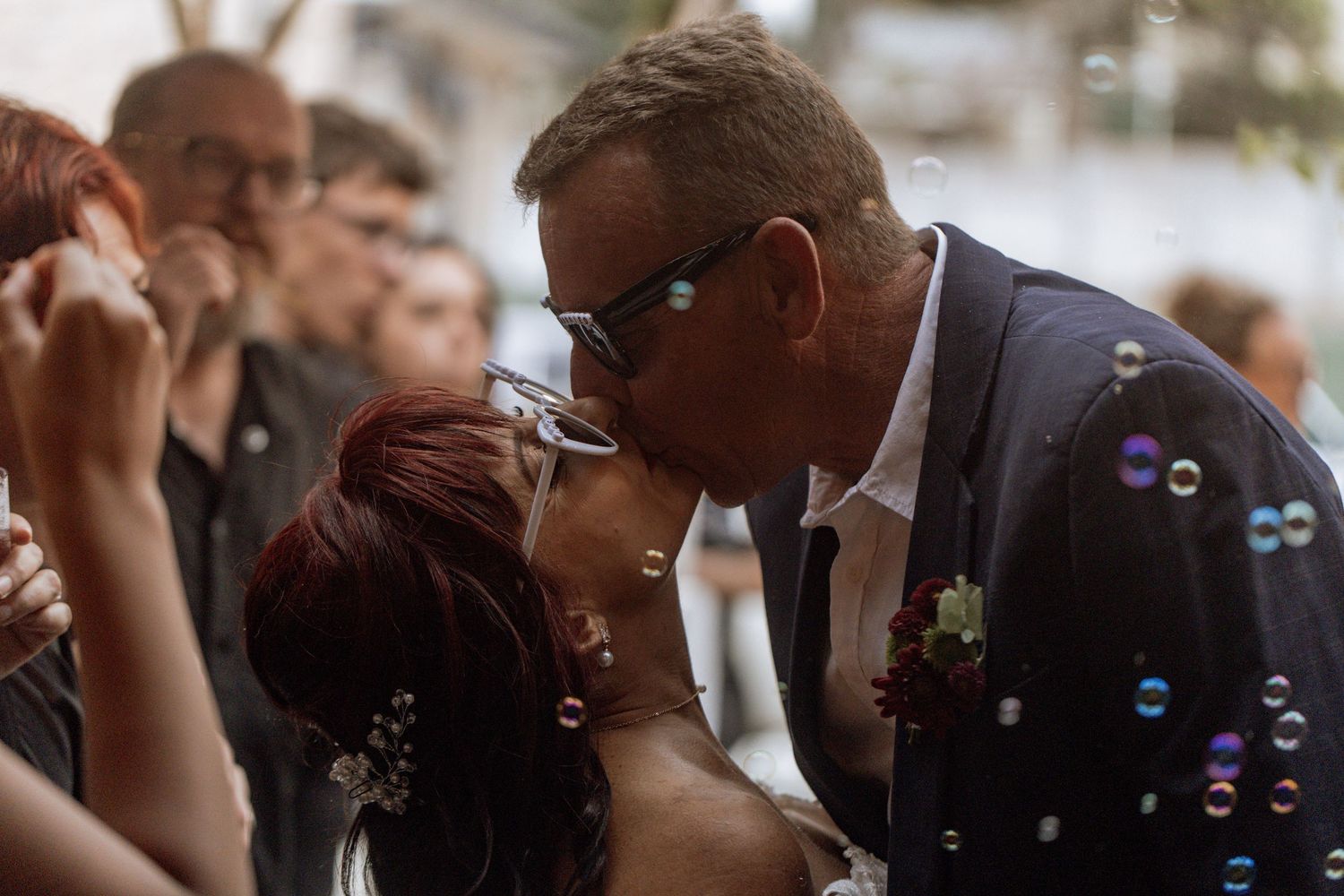 Romantic couple sharing an intimate moment surrounded by floating soap bubbles during an outdoor celebration.