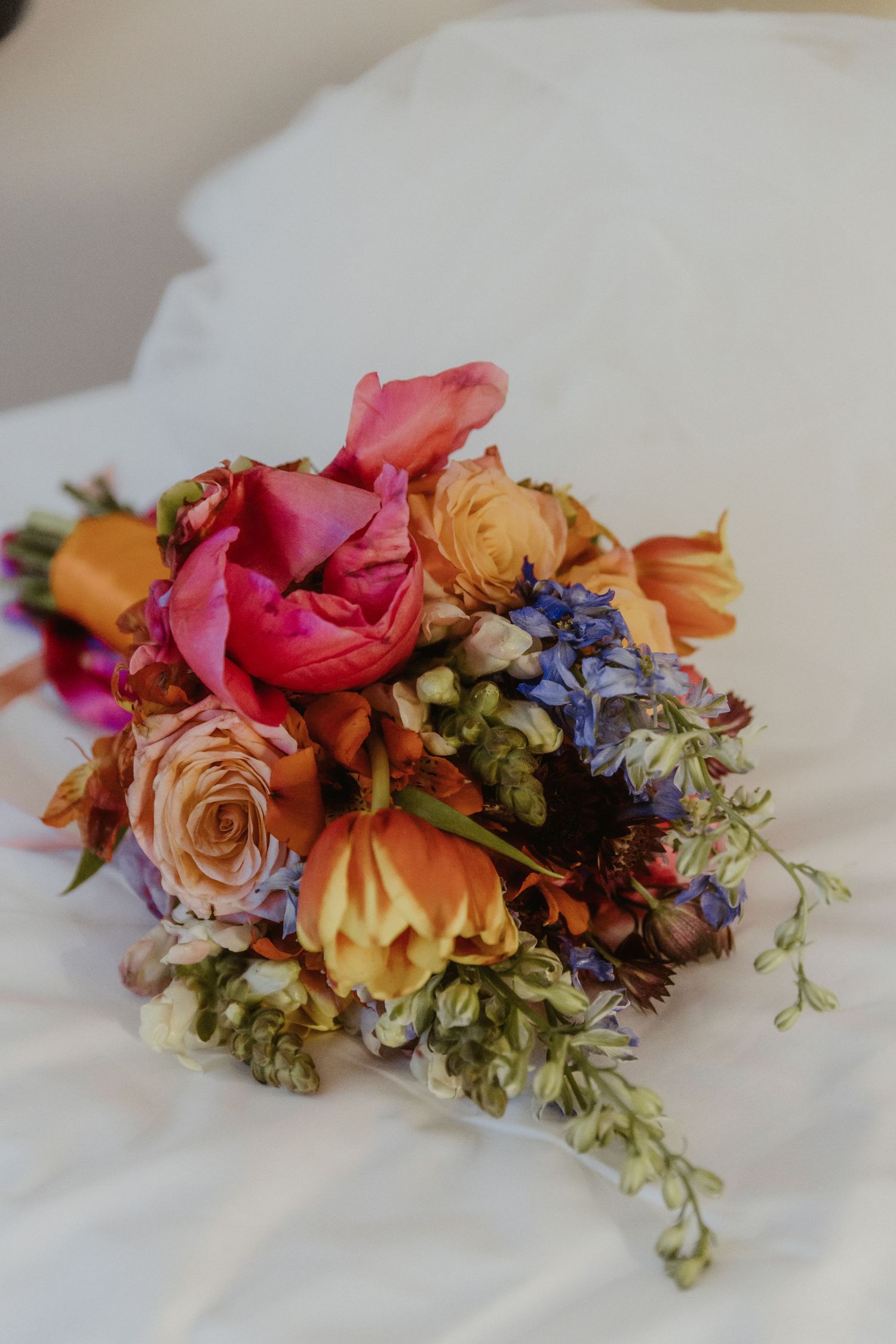 Delicate floral arrangement with peach roses, pink blooms, and blue accents on white linen captured in multiple angles.