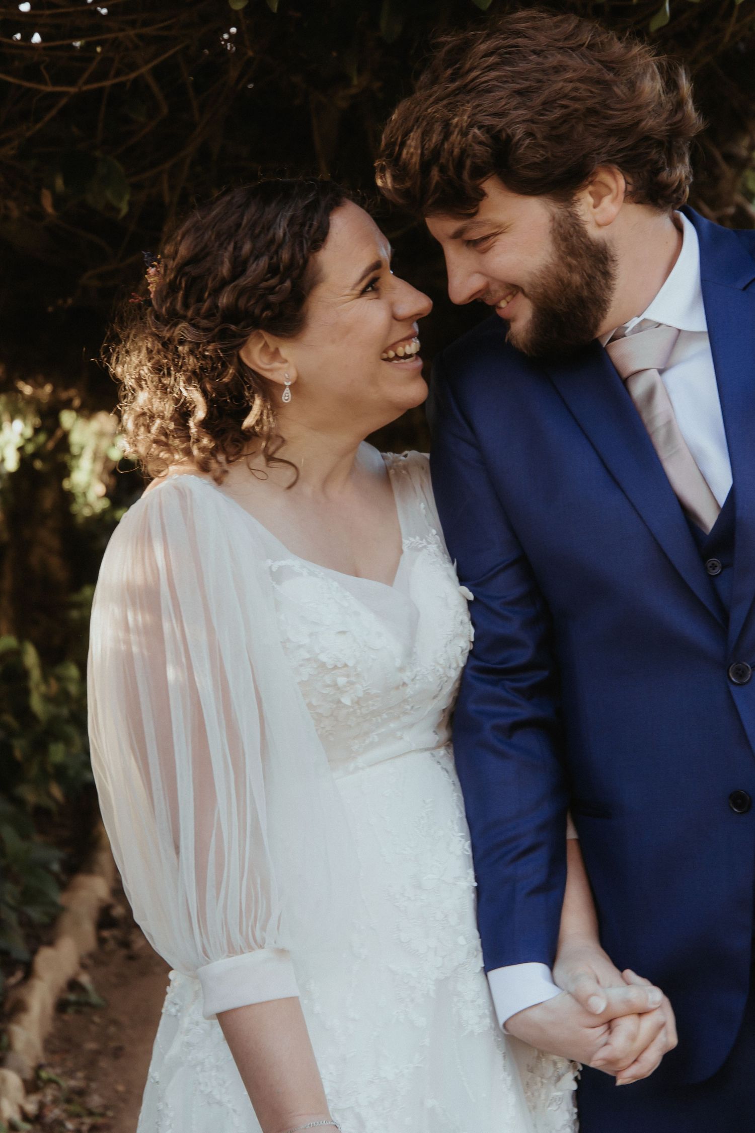 A romantic wedding couple in navy suit and white dress share intimate moments in a series of outdoor portrait photos.