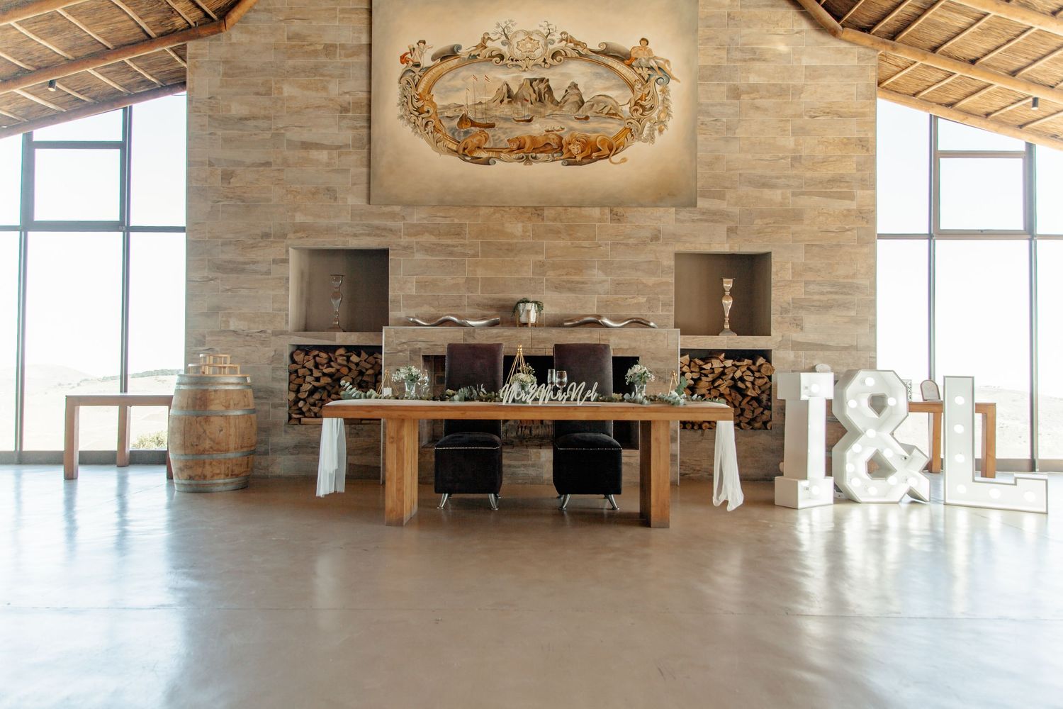 Rustic event venue interior with exposed brick walls, wooden beams, and large windows creating an elegant atmosphere.