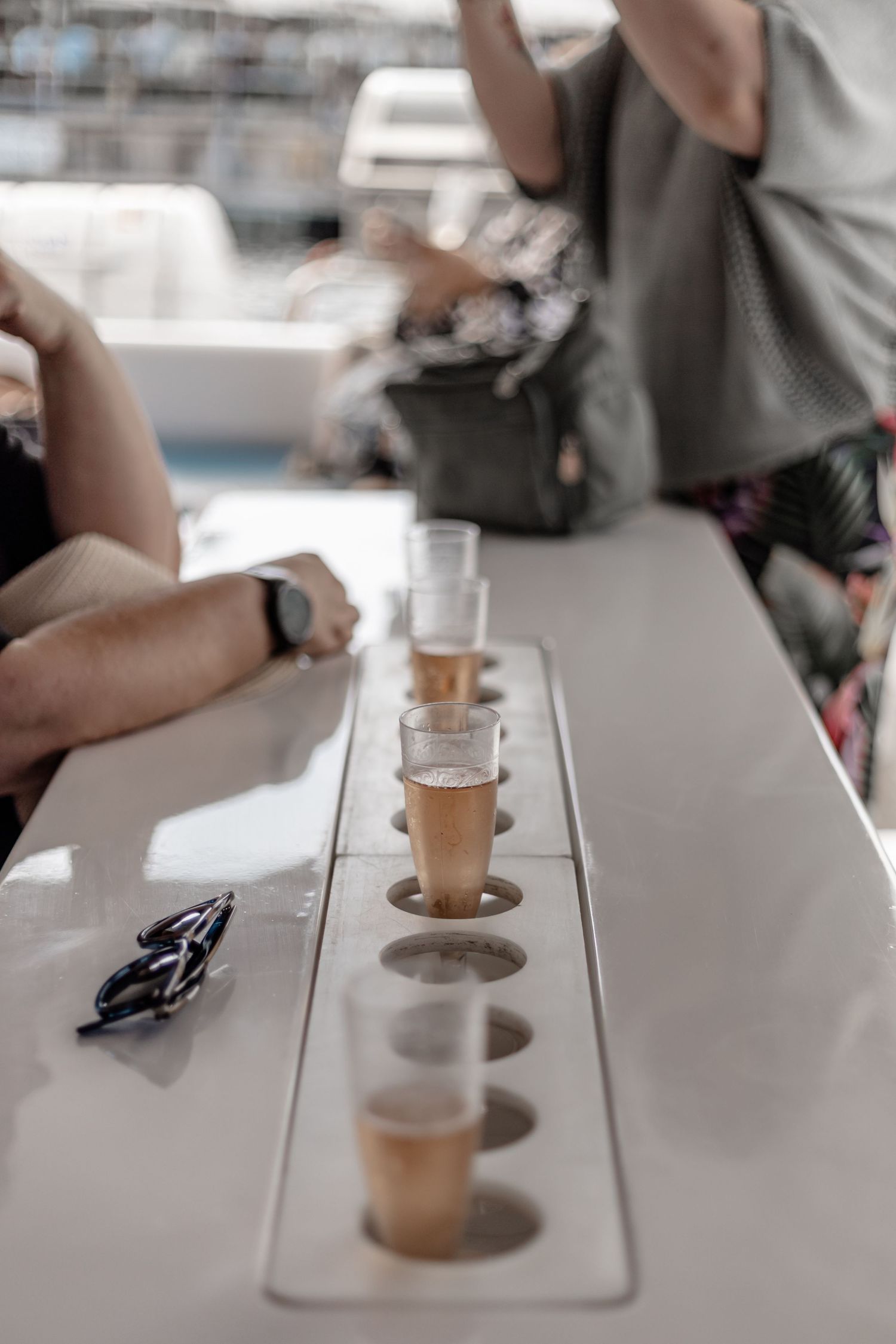 Small shot glasses lined up on a white table surface filled with what appears to be beer or ale for sampling.