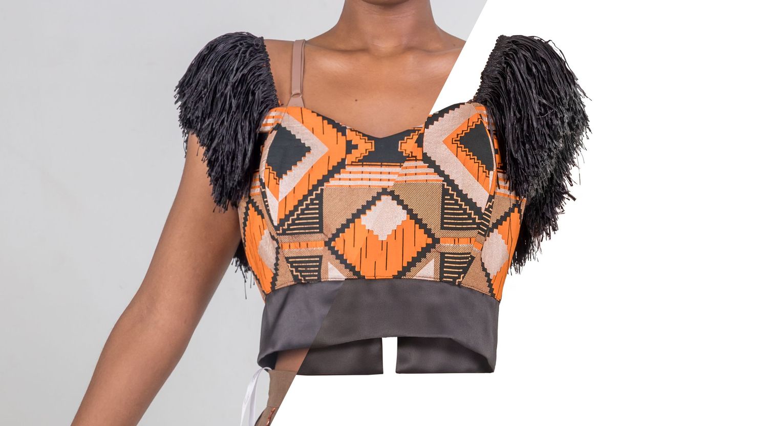 Sleeveless crop top featuring geometric orange and black tribal print with feathered cap sleeves and a wide waistband.