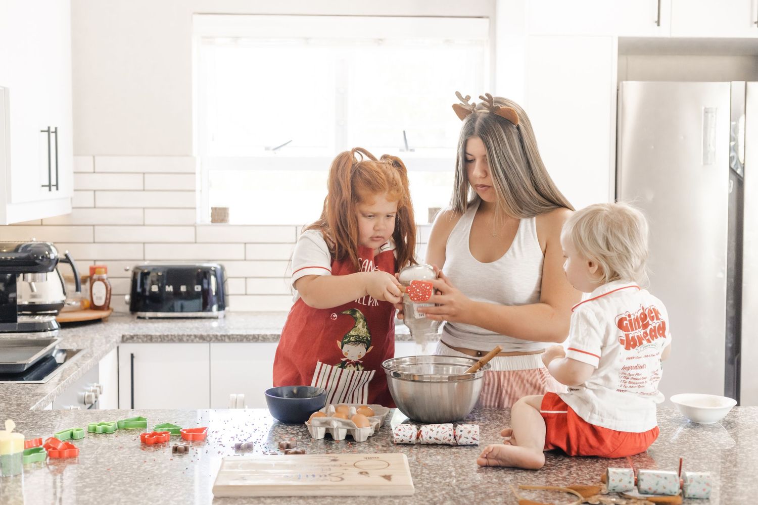 Hands mixing cookie dough ingredients in a white bowl on a bright marble kitchen counter.