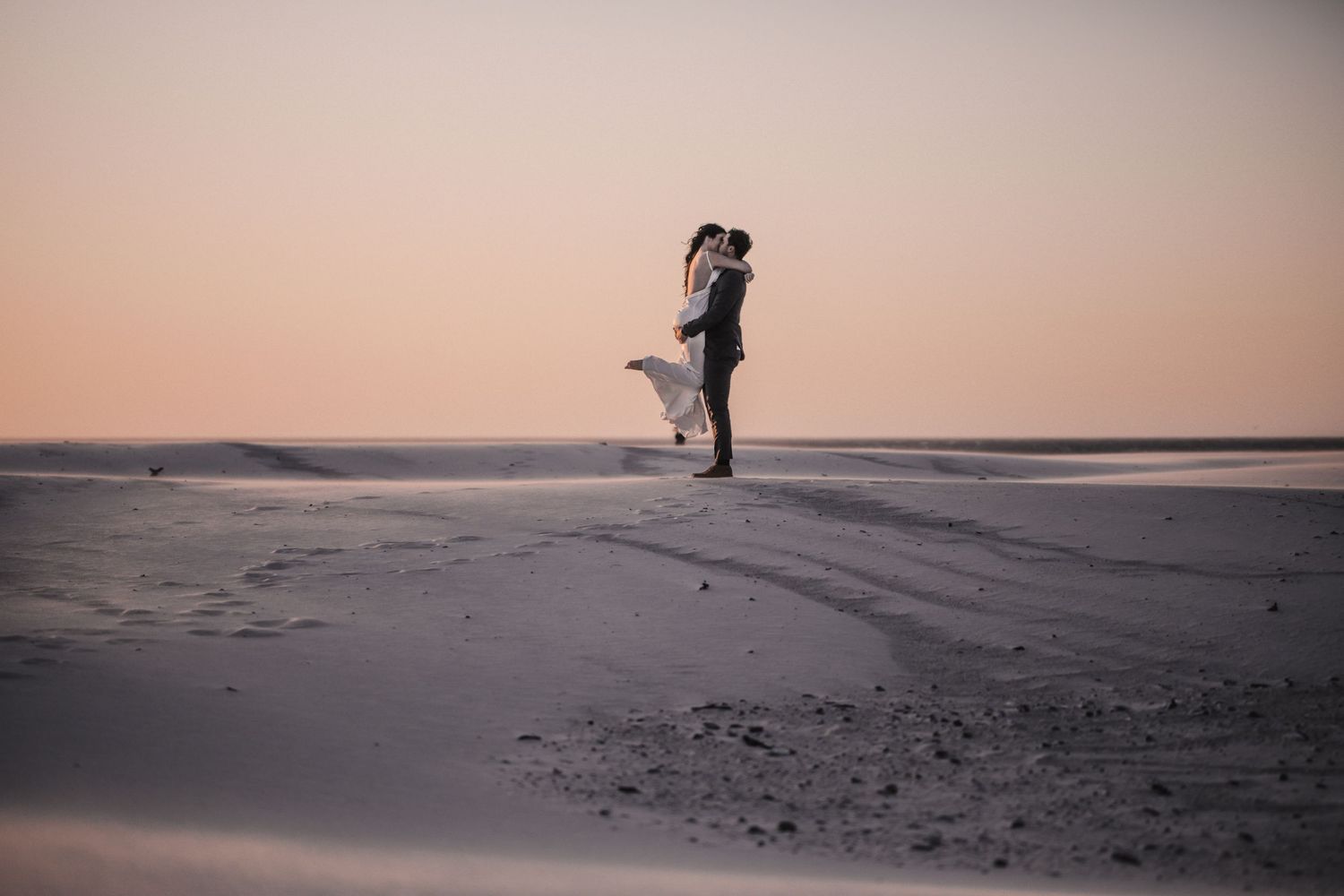 A romantic silhouette of a couple embracing on a misty beach at sunset, creating a dreamy atmosphere.
