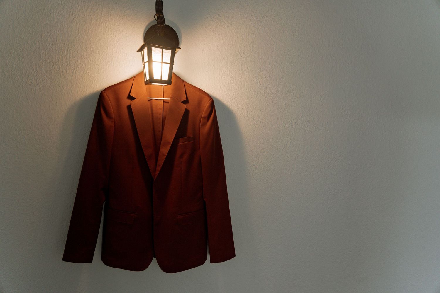 A series of blazers and suit jackets in brown tones arranged in a row against a neutral background.