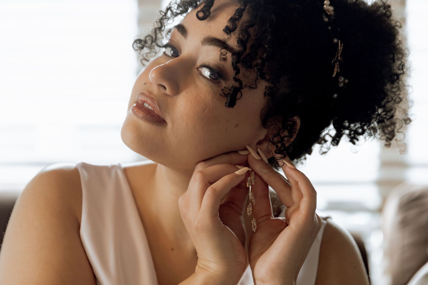 A collection of four beauty portraits showing natural curly hair and glowing skin in warm lighting.