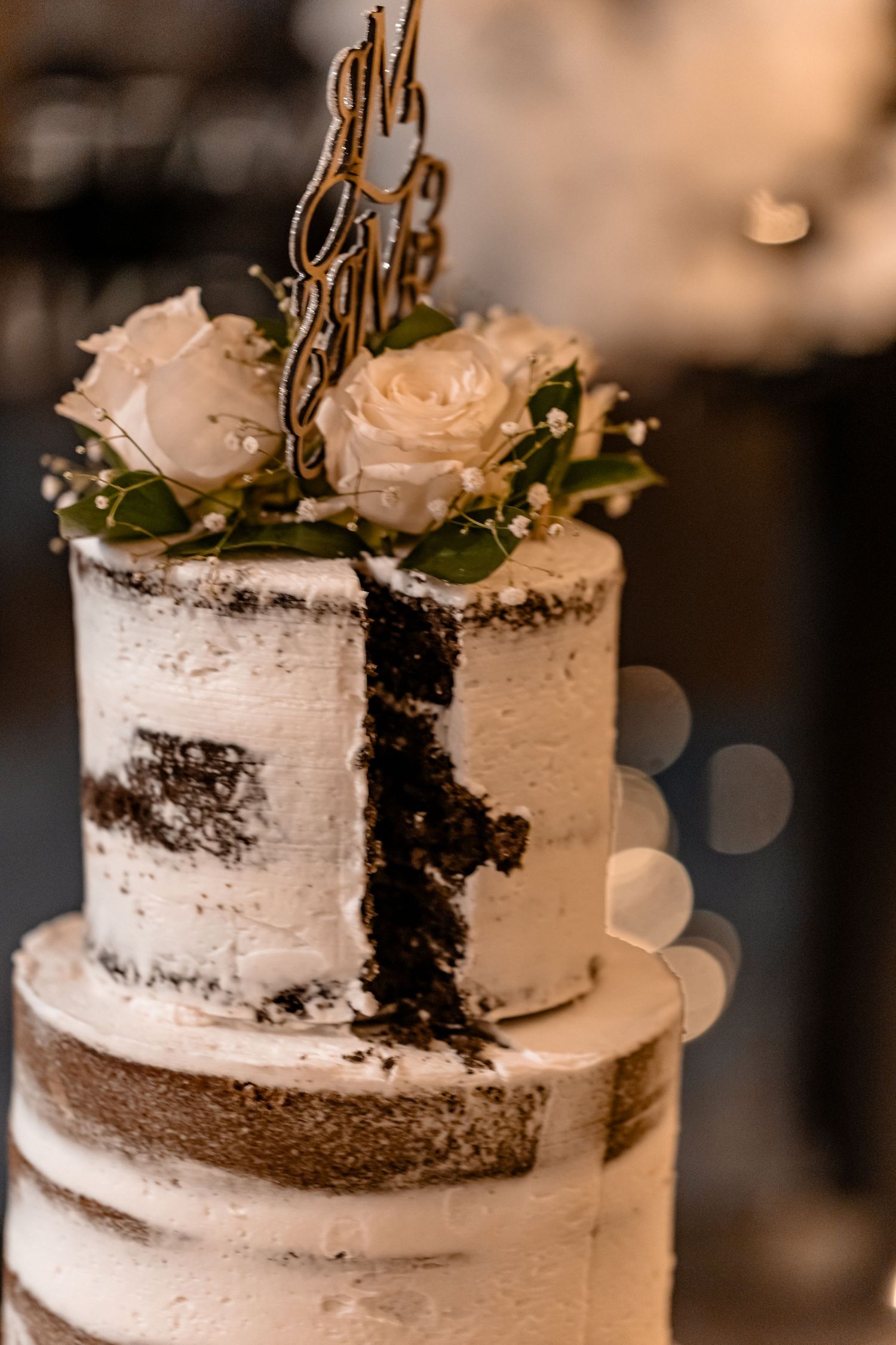 A wedding cake decorated with rustic white frosting and a dramatic chocolate reveal on the side makes an elegant statement.