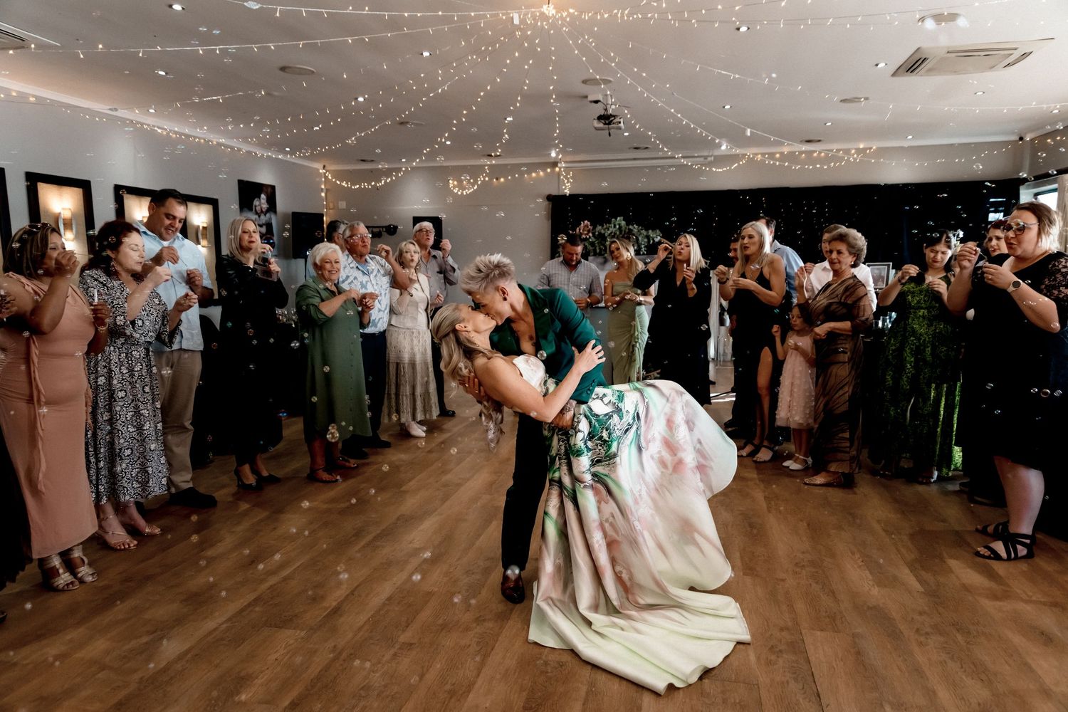 Wedding guests dance and celebrate on an illuminated dance floor during an evening reception.