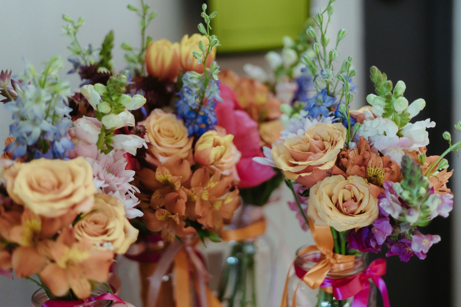 A beautiful floral arrangement featuring peach roses, blue delphinium, and mixed flowers in soft pastel colors.