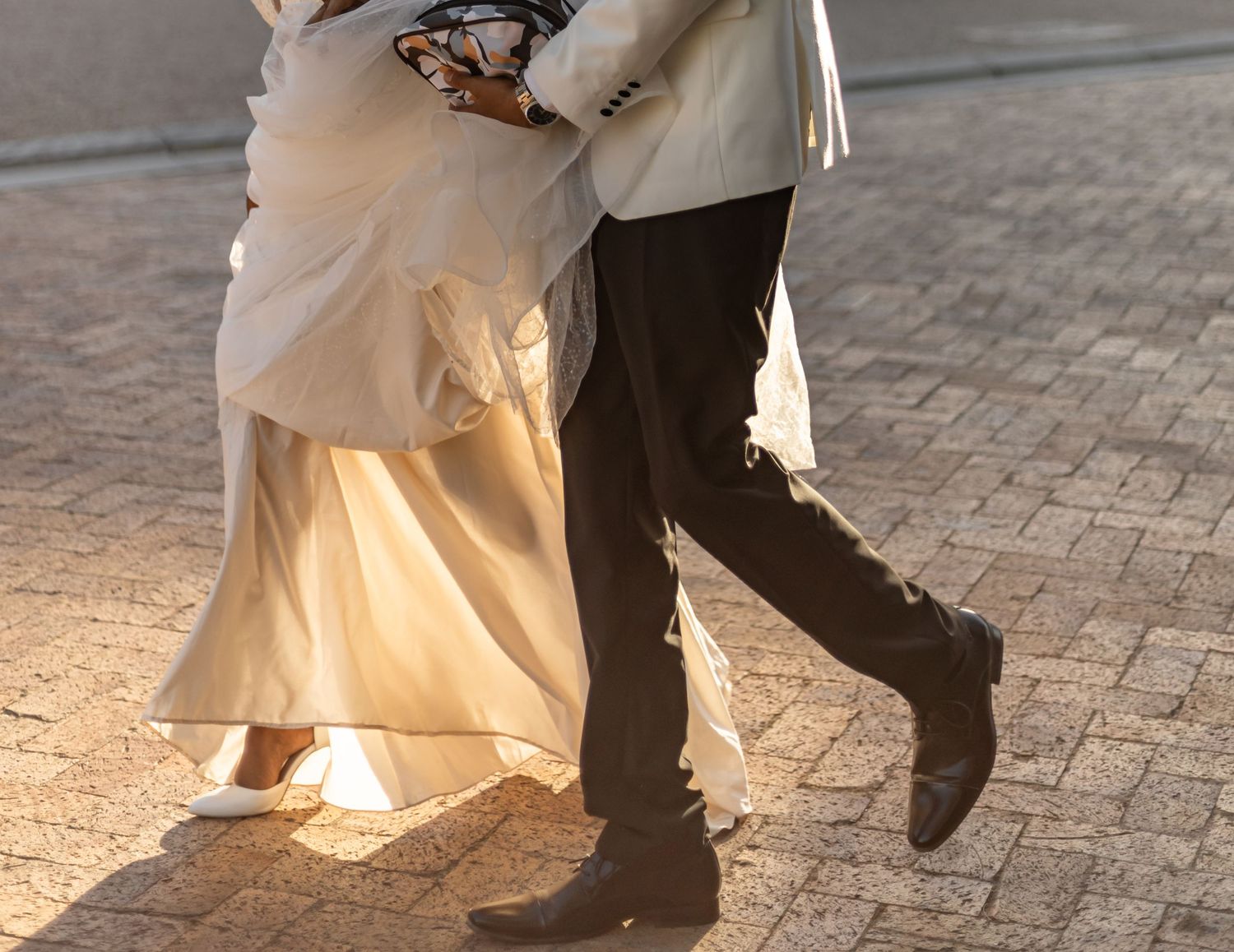 Close-up of wedding couple's feet during a dancing pose on brick pavers.