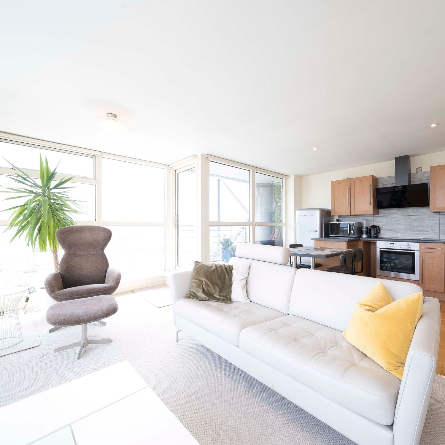 Modern minimalist living room interior with white walls, large windows and contemporary furniture.