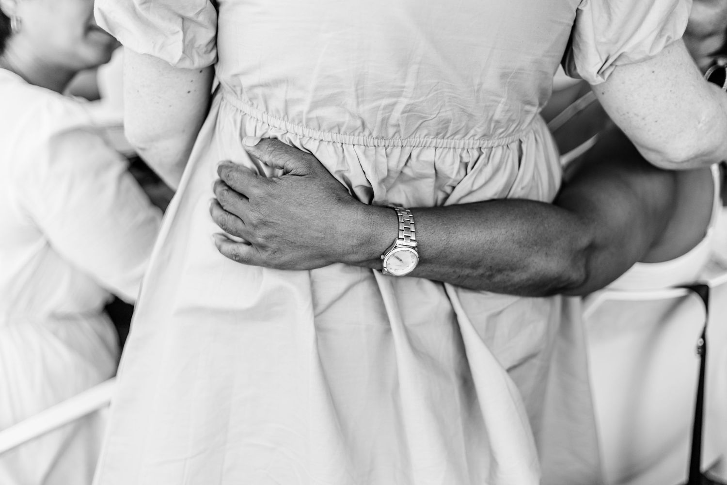 Black and white photo of hands wearing formal attire with a watch detail visible.