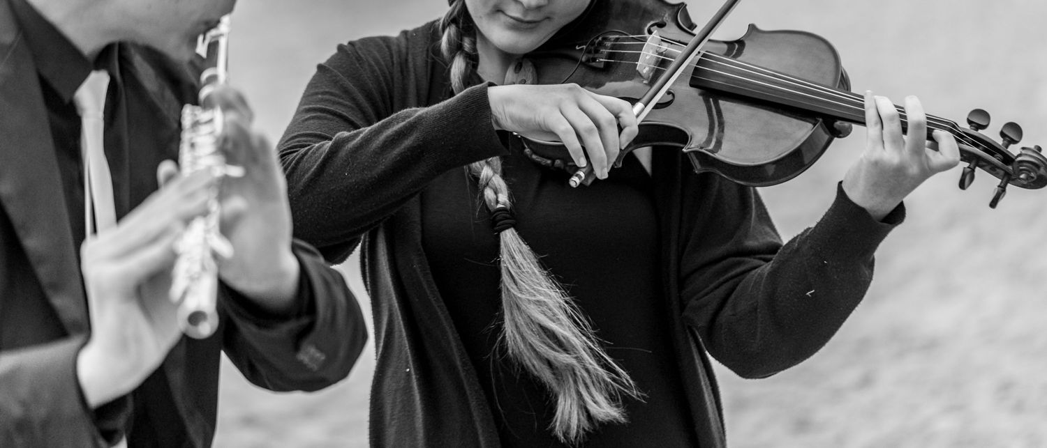 Musicians perform on violins in a black and white collage of close-up performance shots.