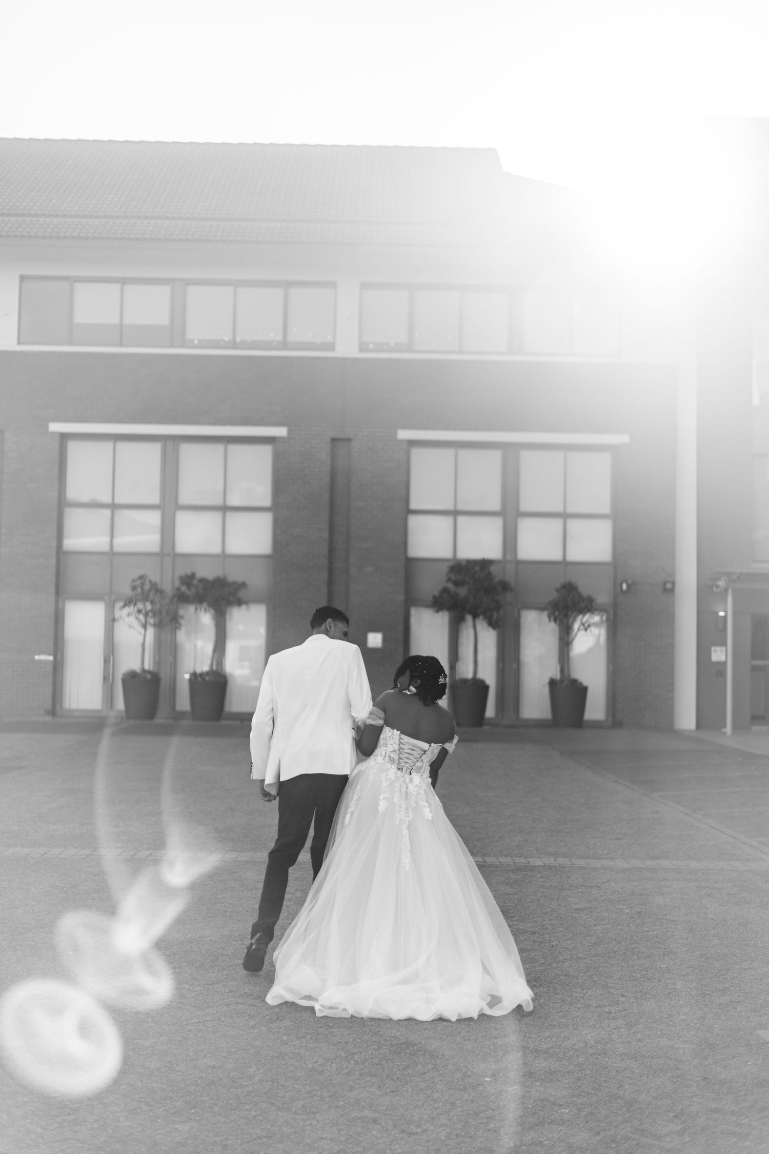 A series of dreamy, backlit wedding photos taken in a large empty space with lens flares and soft lighting.