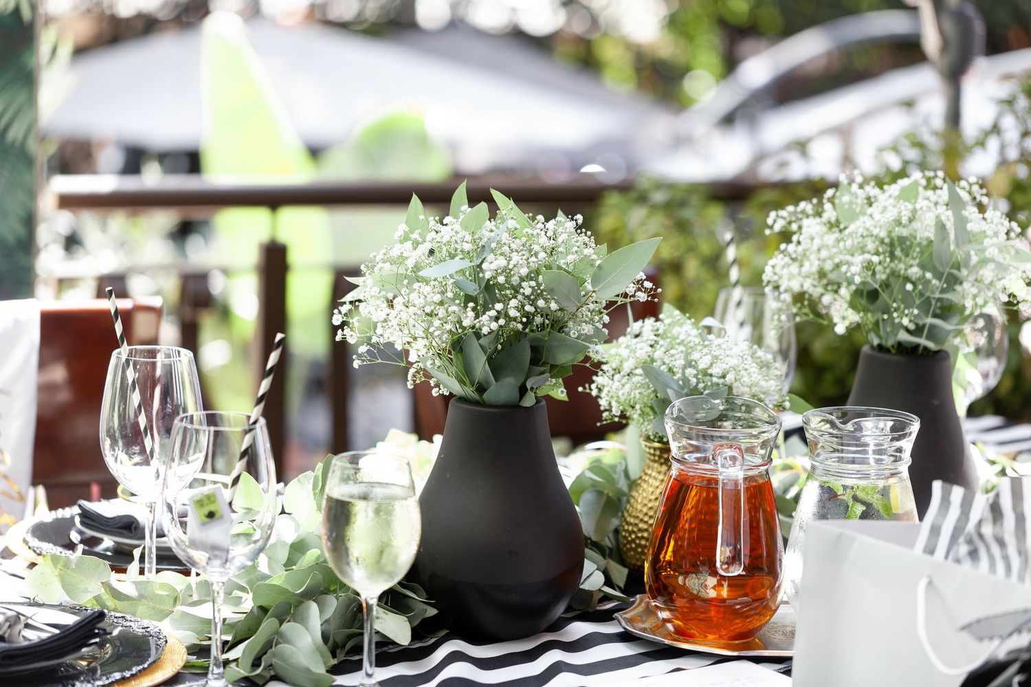 Elegant table setting with white flowers, wine glasses, and honey jars for a rustic outdoor dining experience.