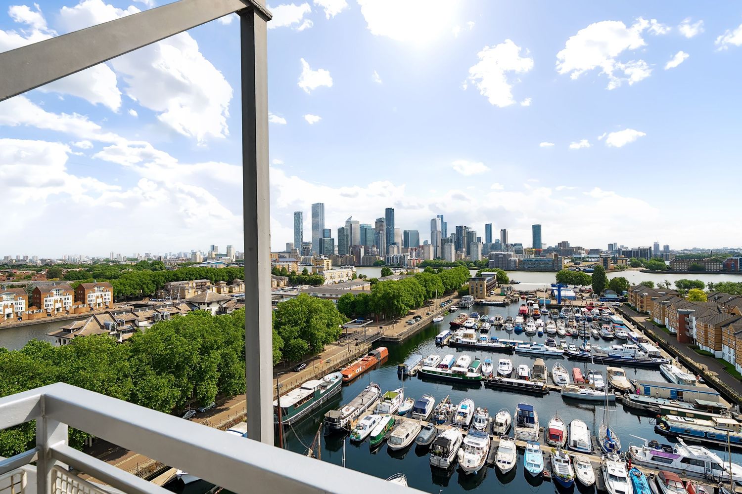 Aerial view of downtown Houston skyline and marina with luxury boats docked under blue sky with white clouds.