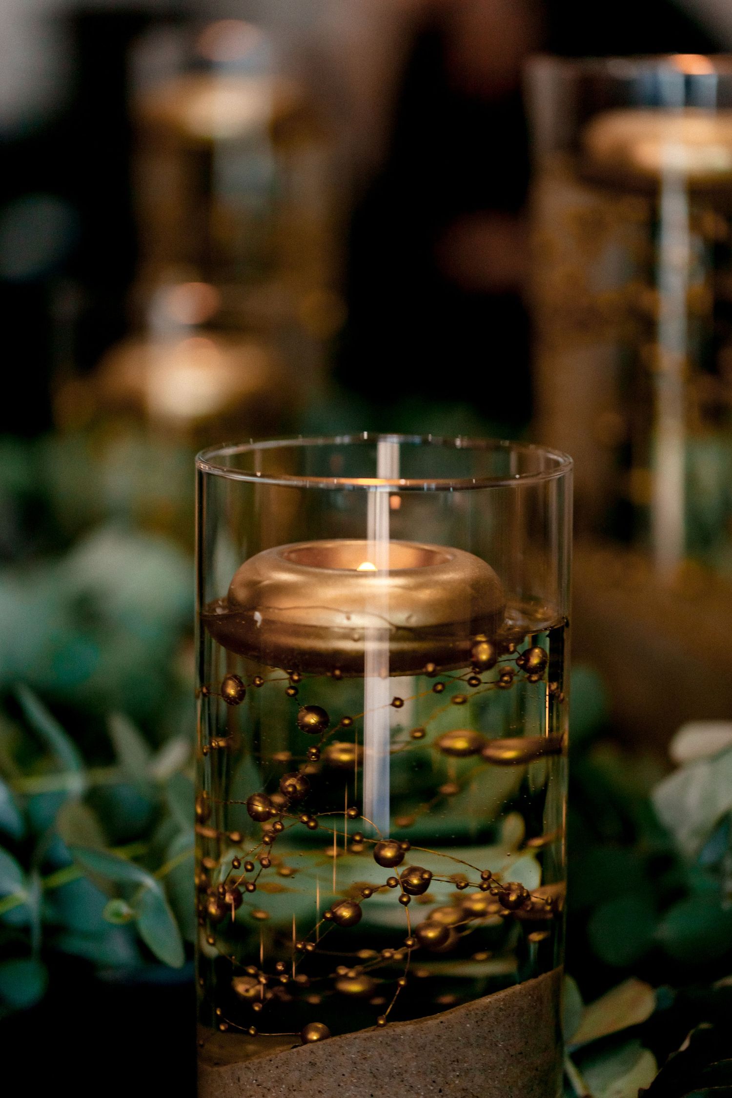 Glass candle holders with golden beads create a romantic ambiance in dim lighting.