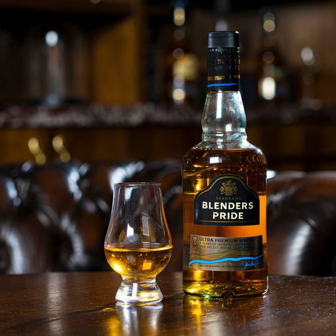 Premium whiskey bottles and tasting glasses arranged on wooden surface in moody bar setting.