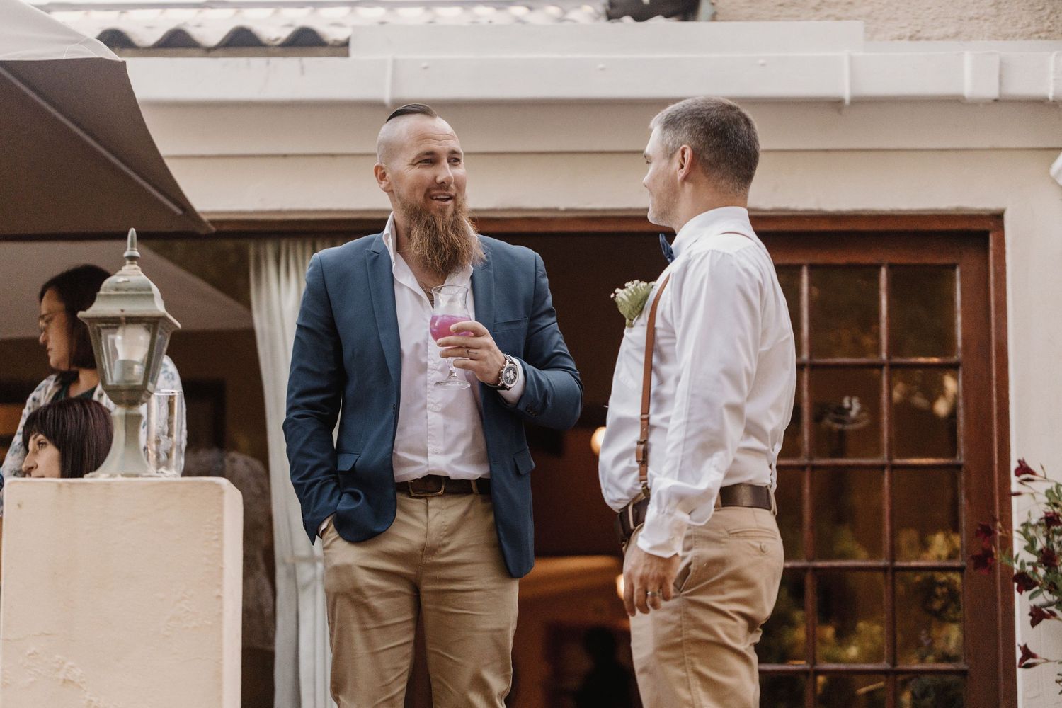 Guests enjoy cocktails and conversation during an elegant outdoor reception at a traditional venue.