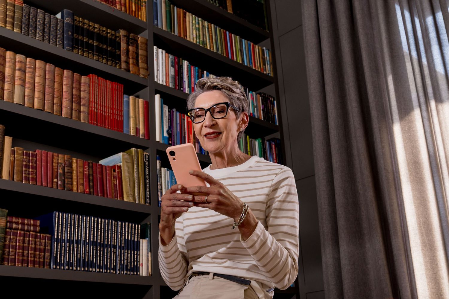 A library bookshelf serves as a backdrop for someone excitedly laughing while holding books.