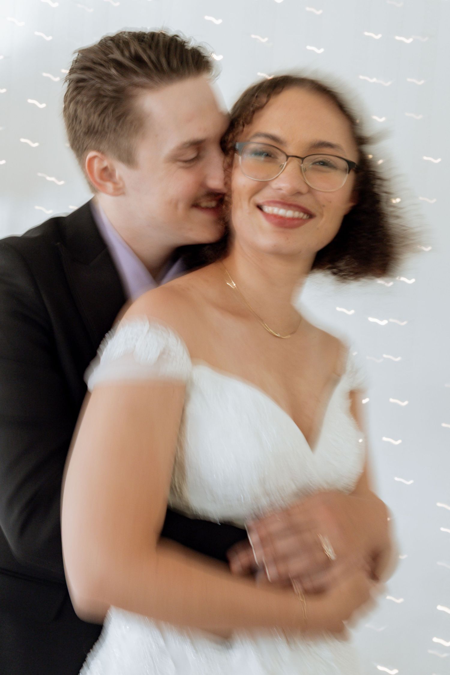 A couple in wedding attire share an intimate moment during a blurred motion photoshoot sequence.