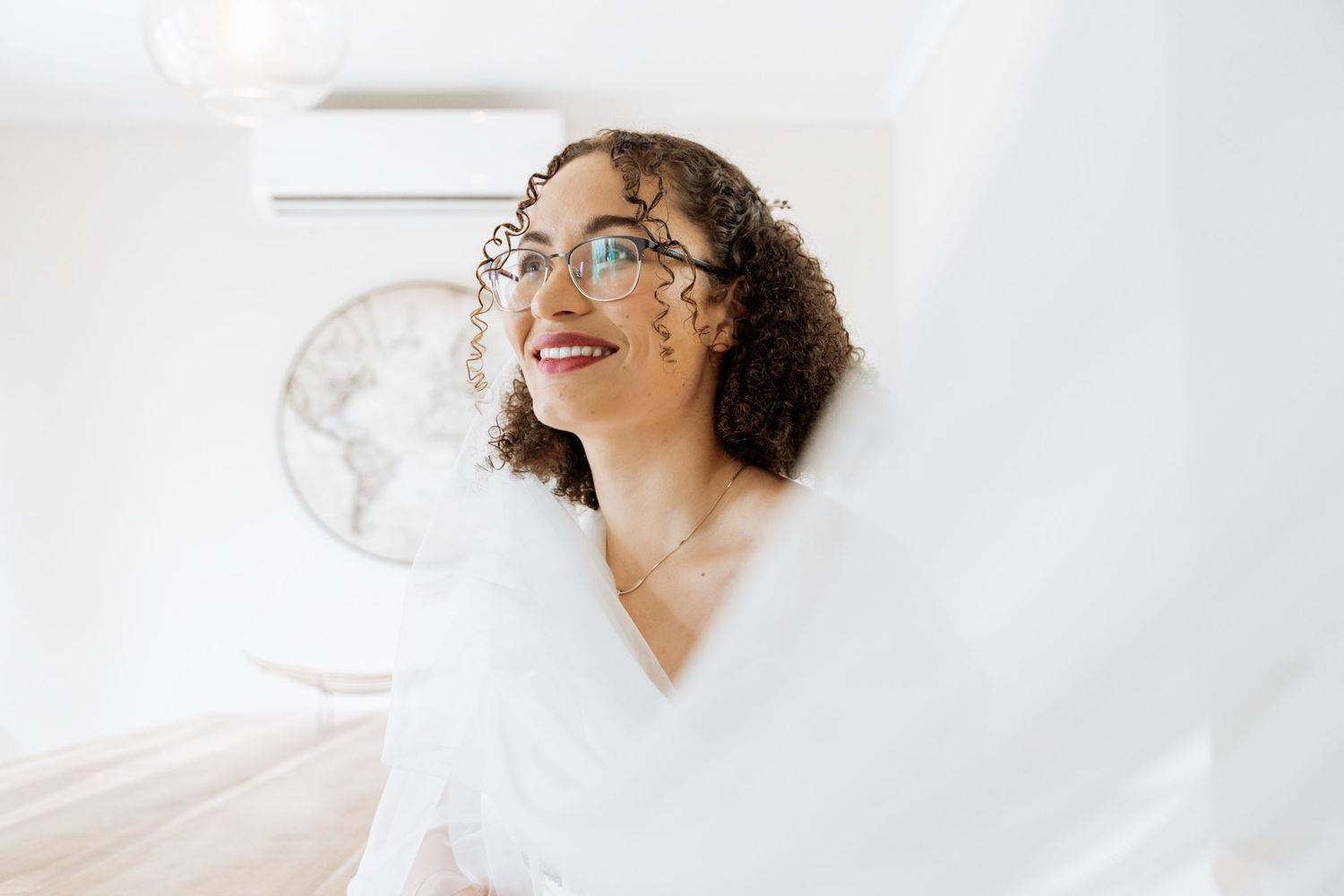 A person in glasses smiles joyfully against a white background in a minimalist portrait series.
