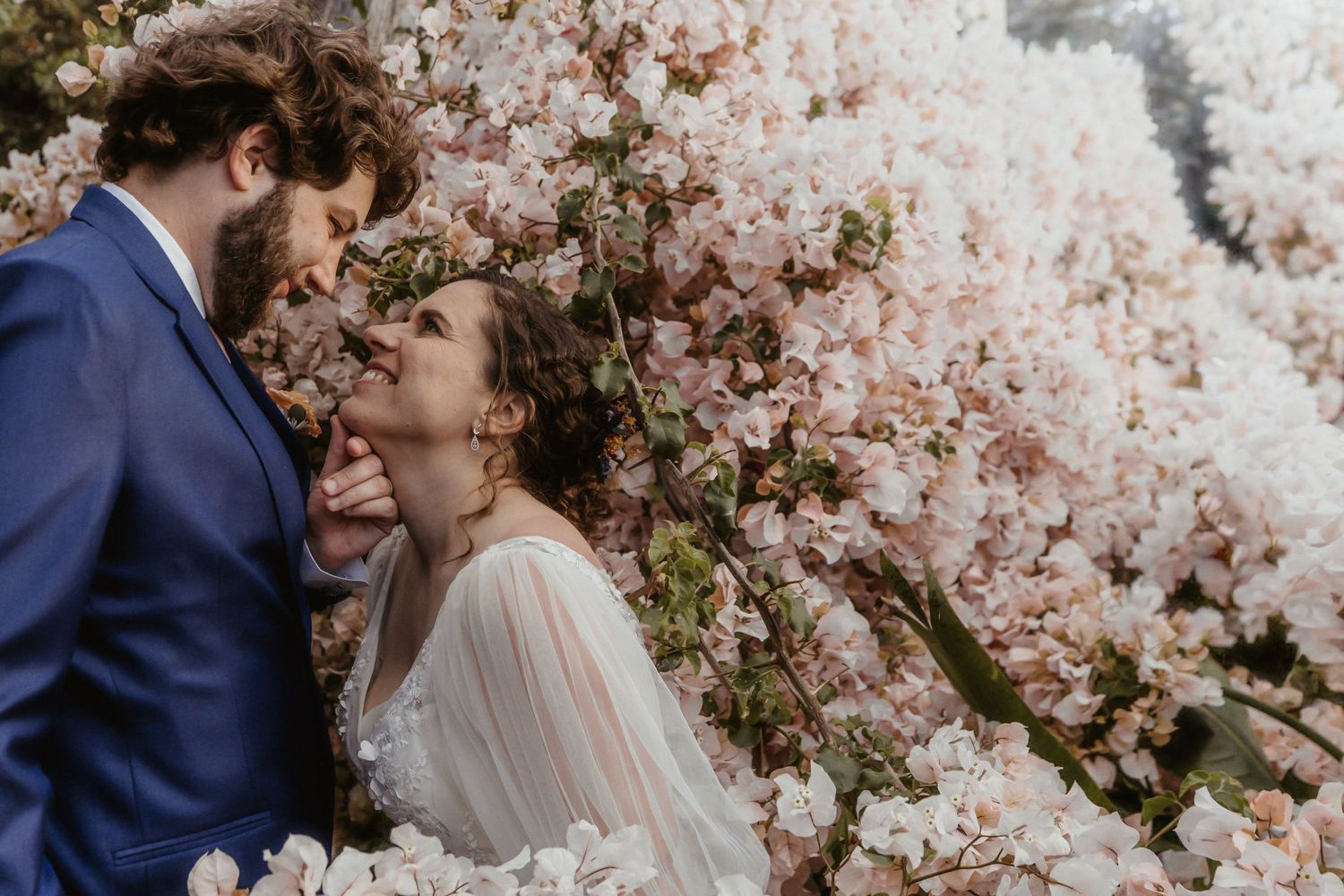 A romantic couple embraces under blooming cherry blossom trees during a spring wedding photoshoot.