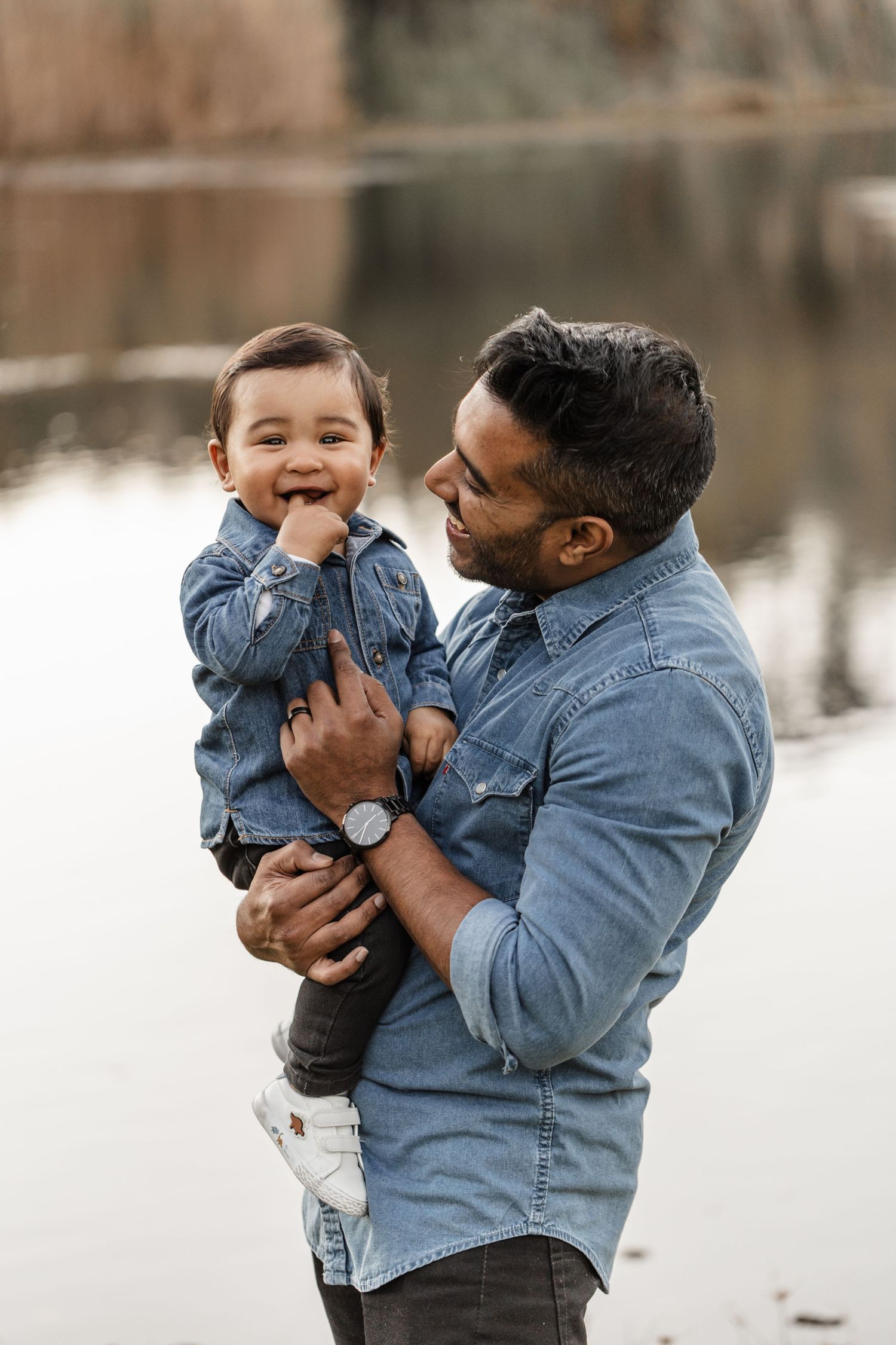 A parent and child share joyful moments together while wearing matching denim jackets outdoors.