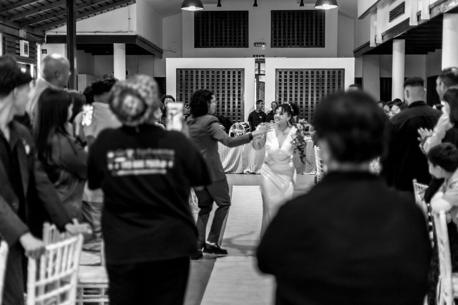 A crowded black and white scene of people dancing and mingling at what appears to be a party or social gathering.