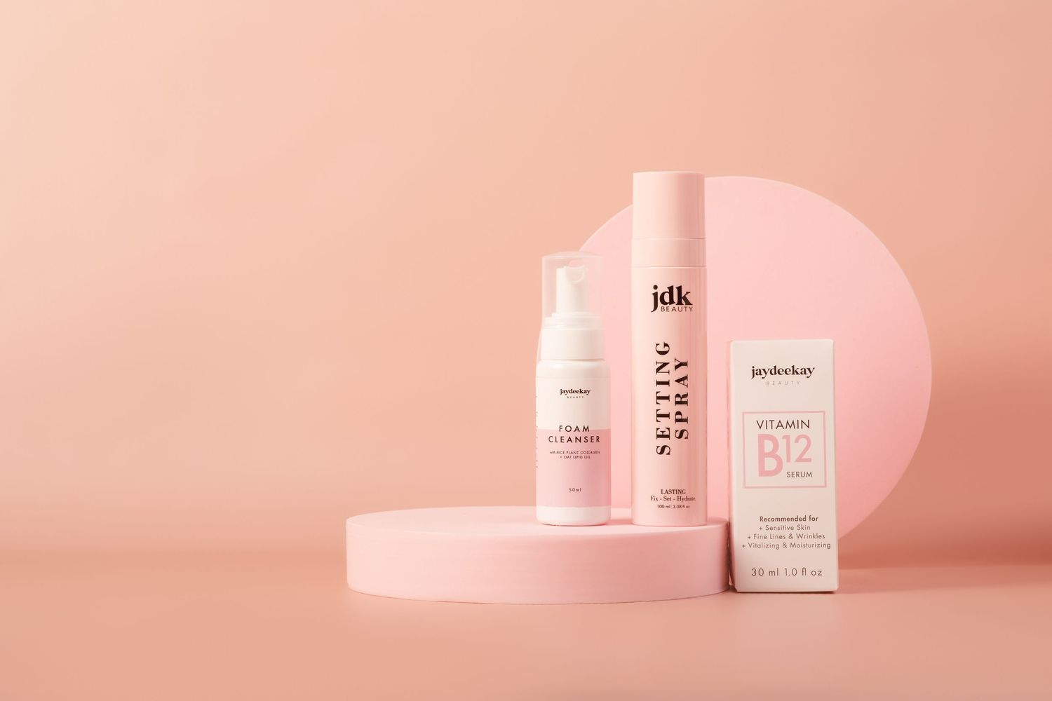 Pink beauty products and skincare bottles arranged minimally against a soft coral background in a modern layout.