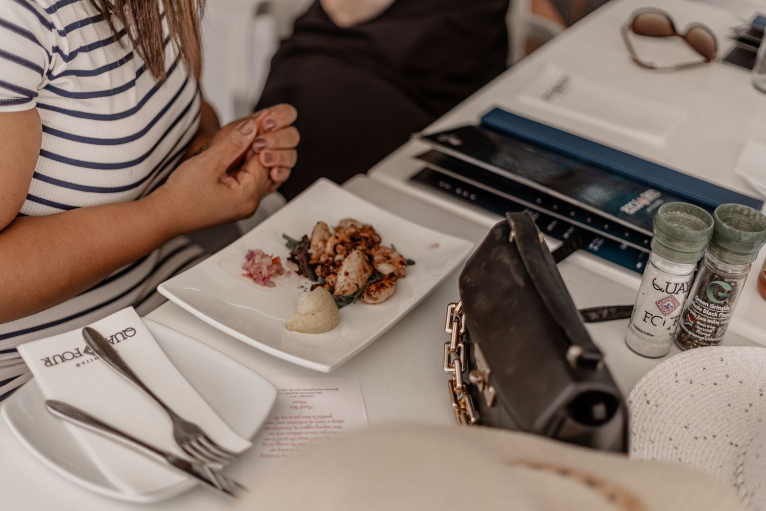 Close-up of a dining table setting with a plate of food, utensils and glasses.