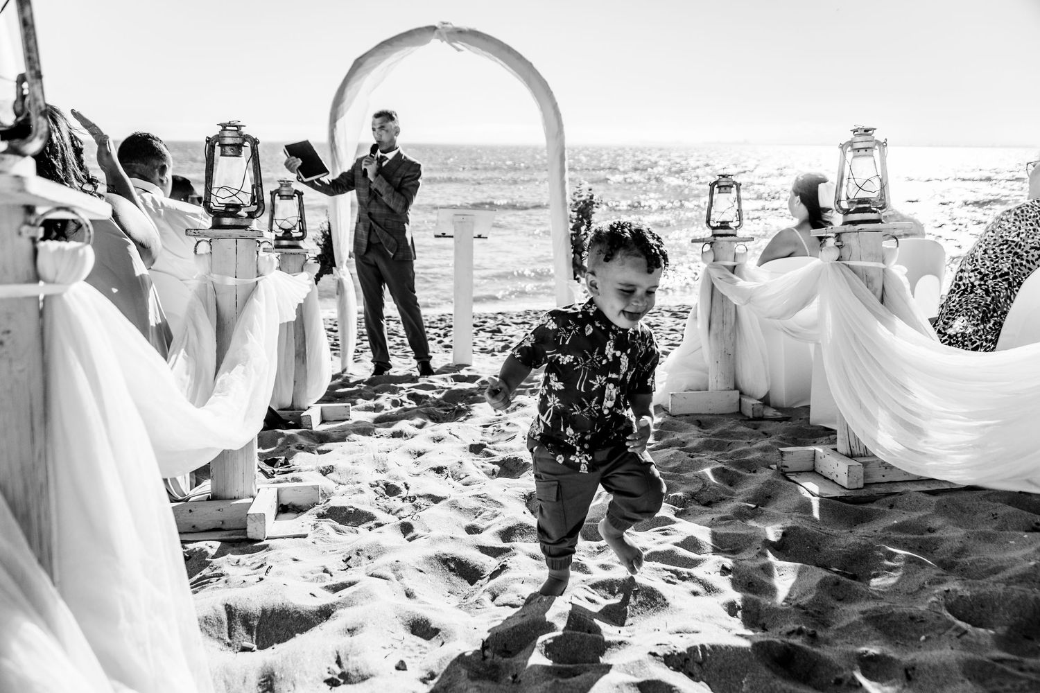 Series of black and white beach wedding ceremony photos showing guests and decor against an ocean backdrop.