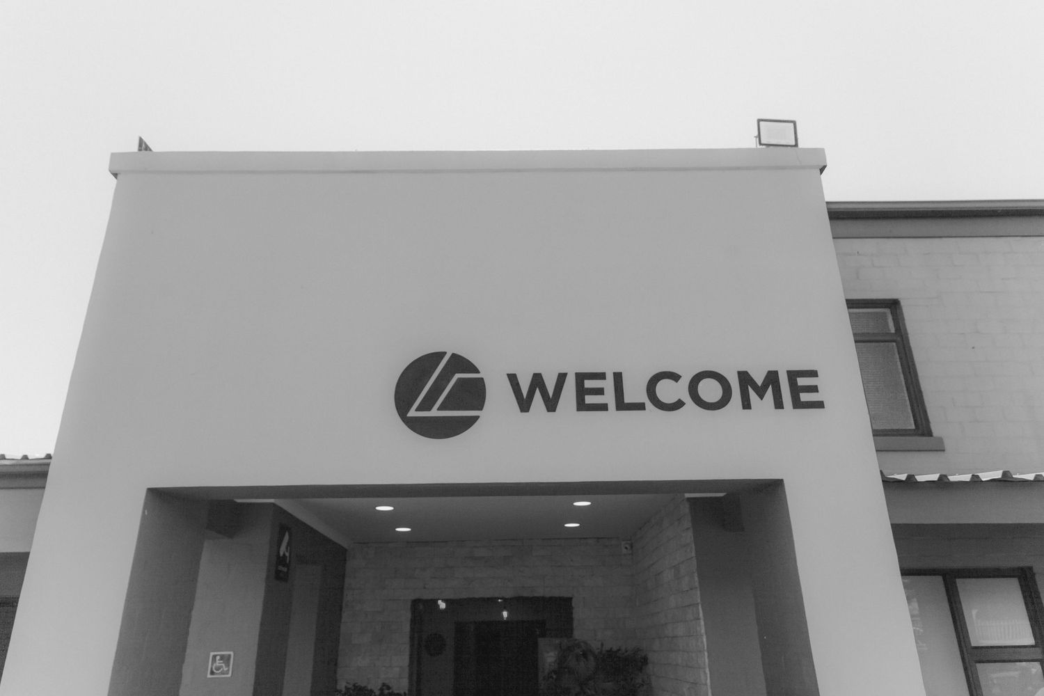 A modern retail storefront with a large WELCOME sign mounted on the exterior wall of a commercial building.