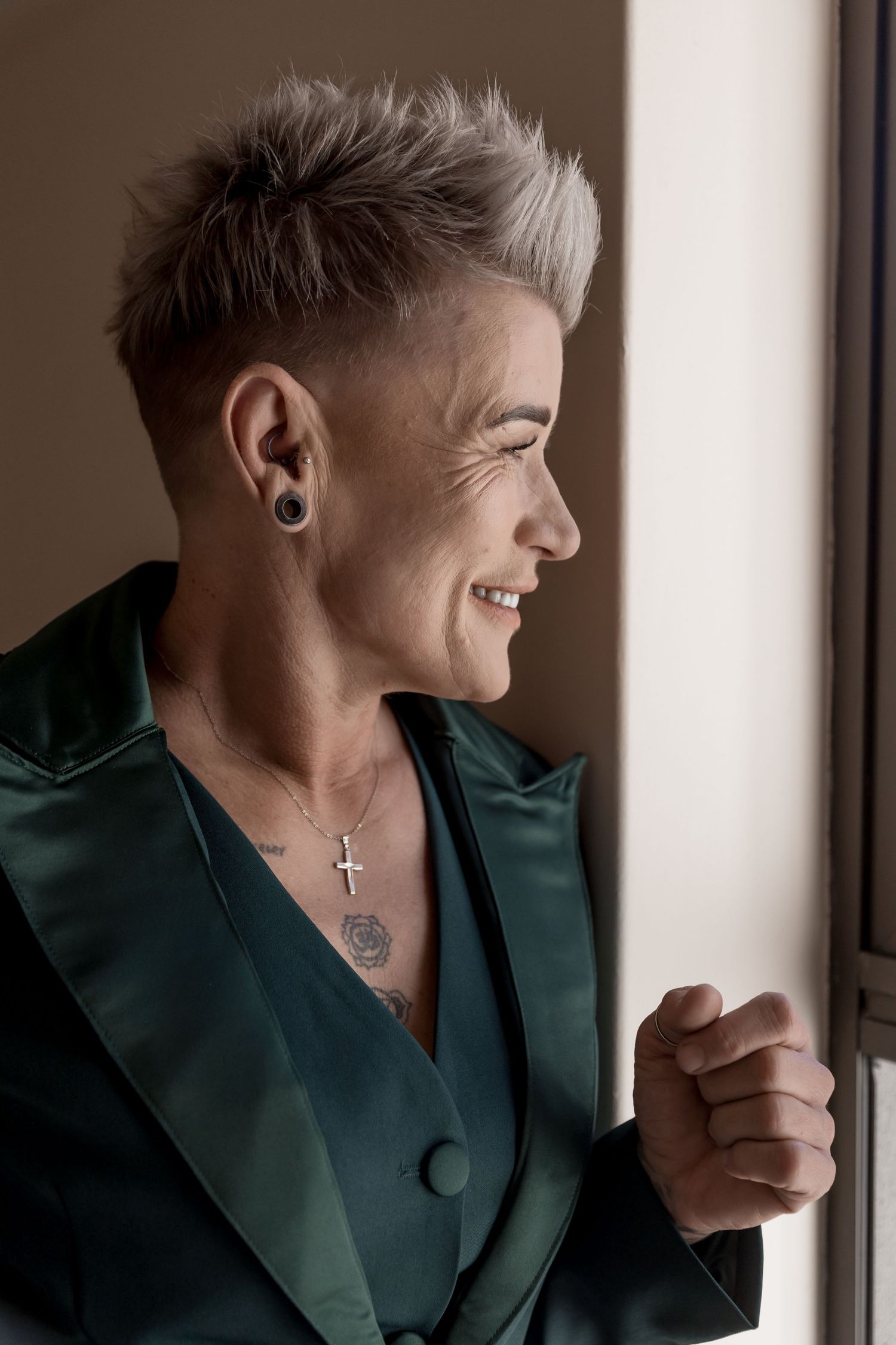 Four sequential portraits showing a person with short platinum hair and ear piercings wearing a dark green blazer.
