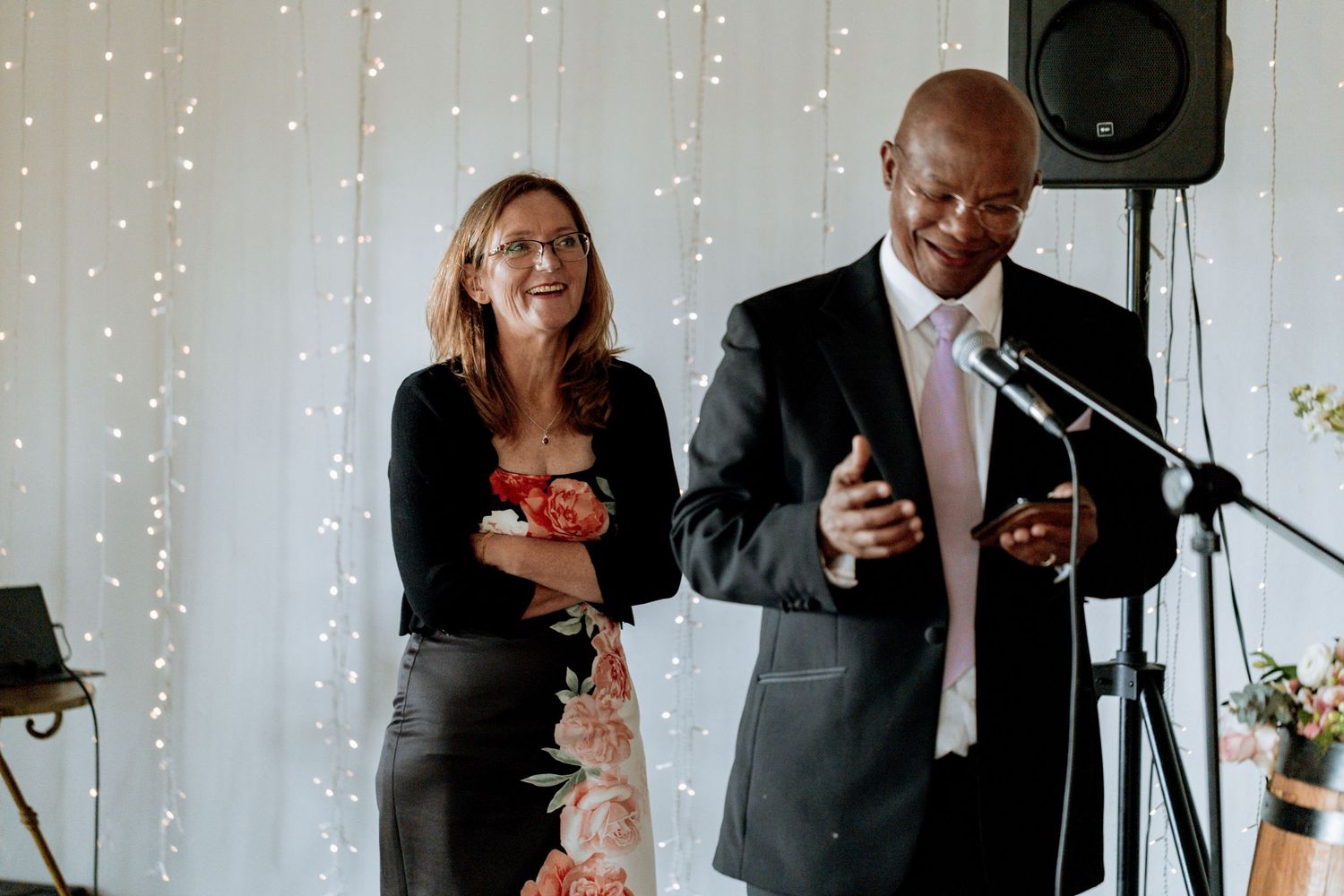 A joyful toast shared between wedding attendees in formal attire during an evening reception with twinkling lights.