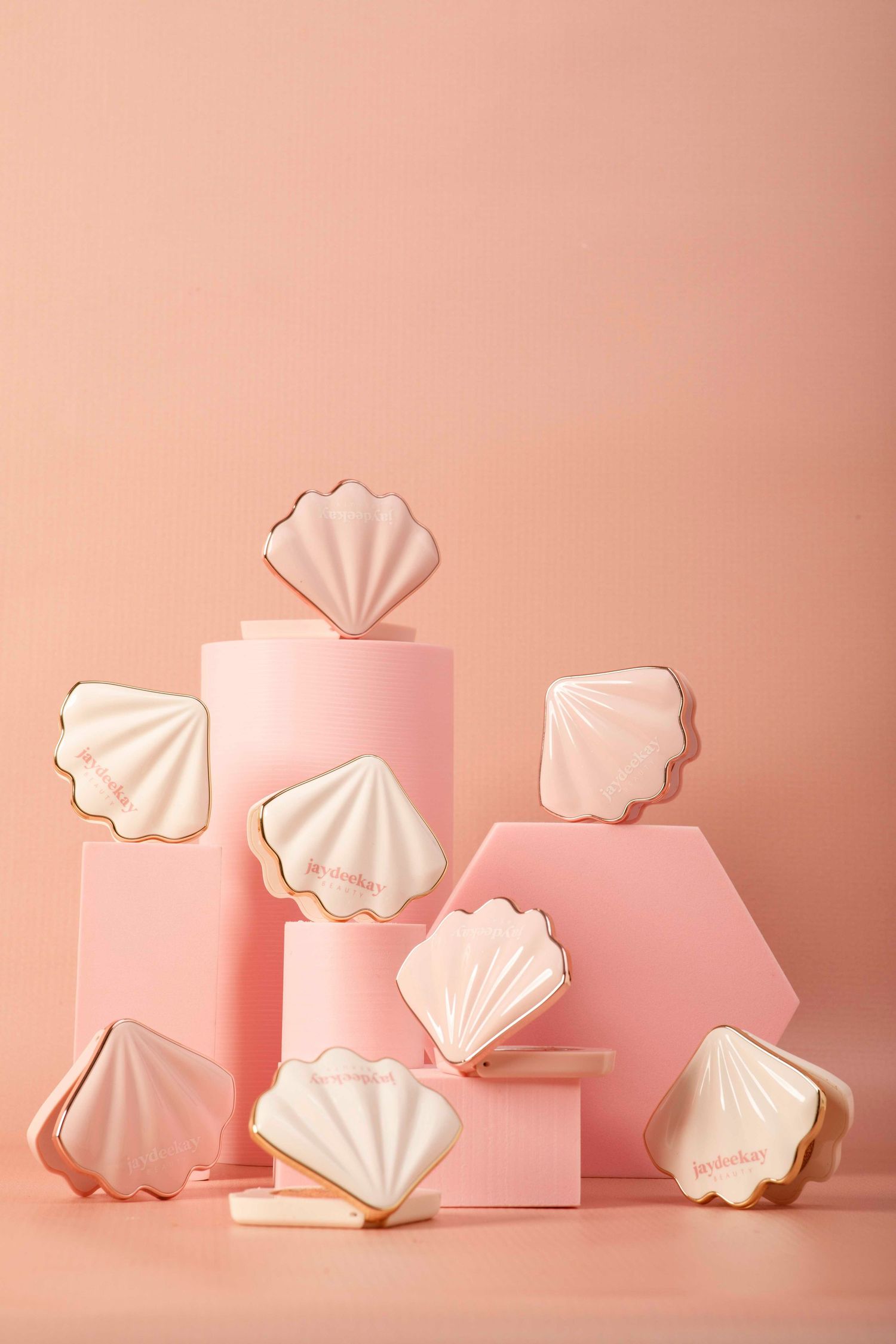White seashell-shaped ceramic pieces arranged in a minimalist composition against a soft pink background.