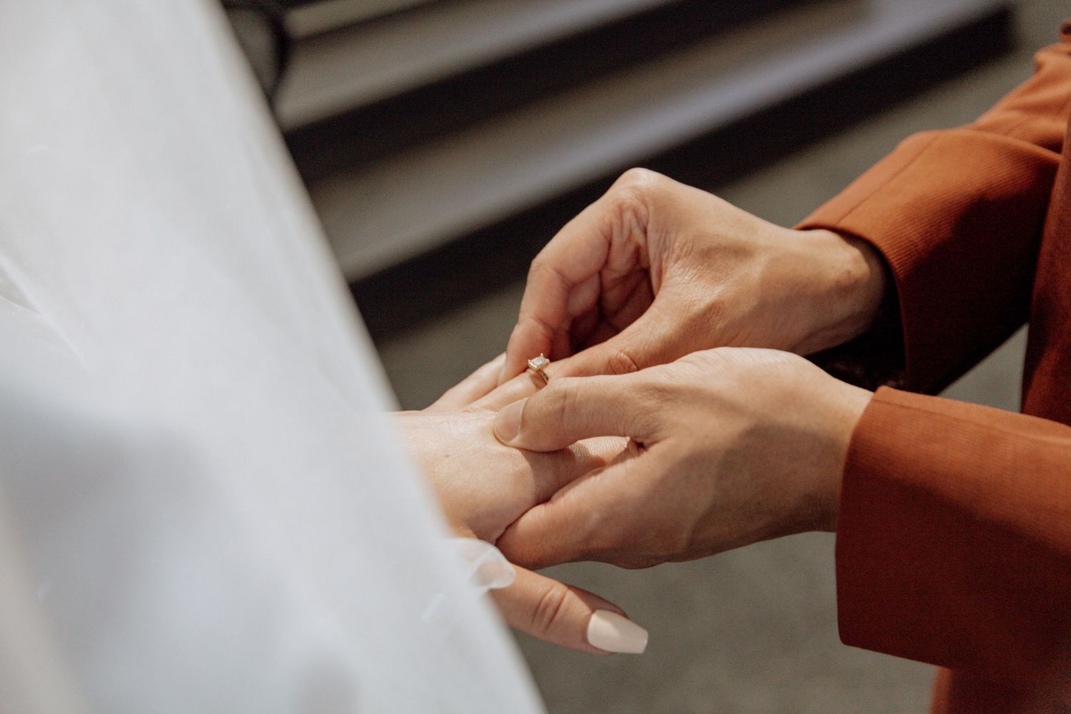 Close-up view of two hands gently holding each other in tender embrace with soft lighting.