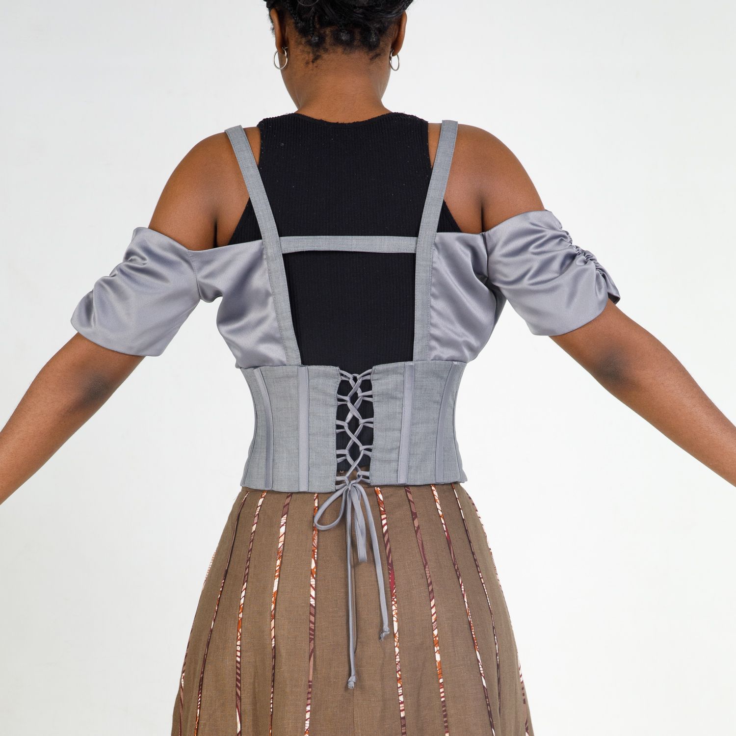Close-up view of a brown skirt with silver sequin stripes paired with a grey and black color block top.