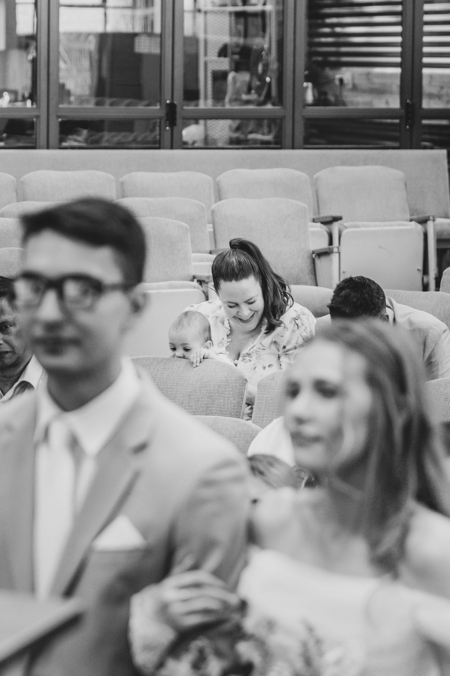 Wedding guests laugh together during reception in black and white photograph.